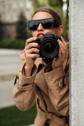 Photo of Private detective with modern camera spying outdoors, focus on lens