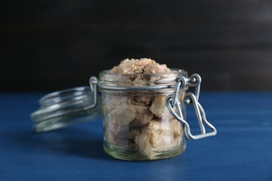 Photo of Glass jar of tasty cod liver on blue wooden table