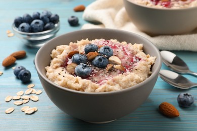 Tasty oatmeal porridge with toppings on light blue wooden table