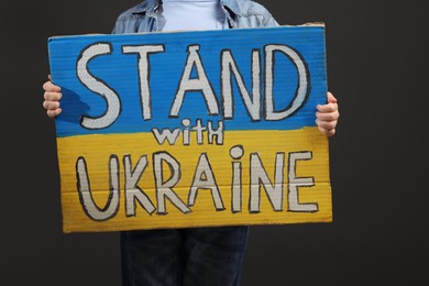 Photo of Boy holding poster Stand with Ukraine against grey background, closeup