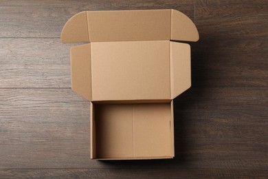 Empty open cardboard box on wooden table, top view