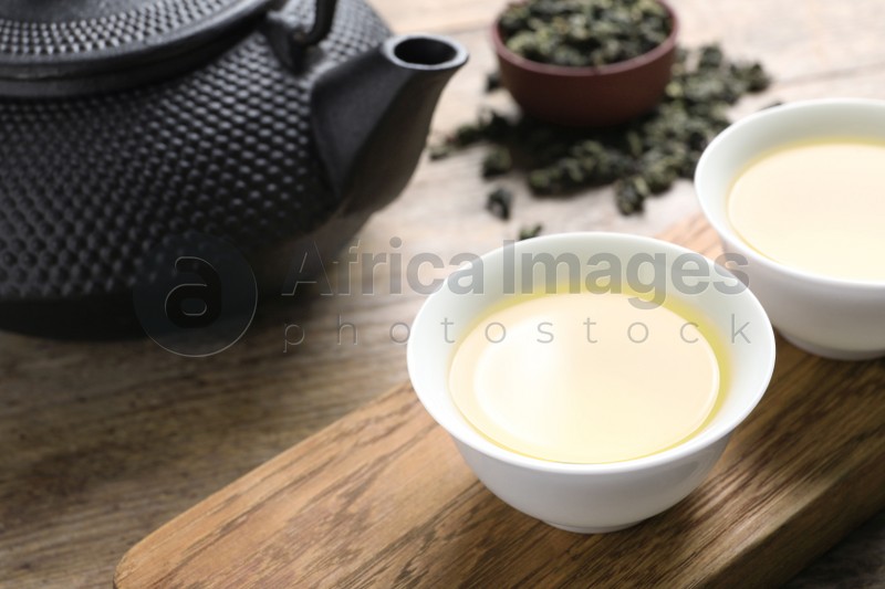 Cups and teapot of Tie Guan Yin oolong on wooden table. Space for text
