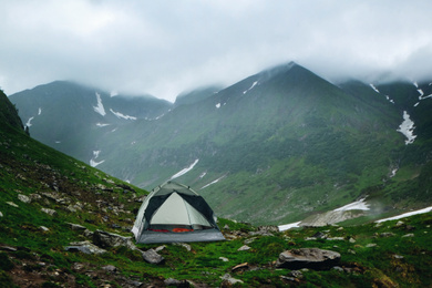 Camping tent with sleeping bags near beautiful foggy mountains