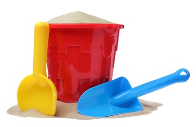 Plastic toy bucket with colorful shovels and sand on white background
