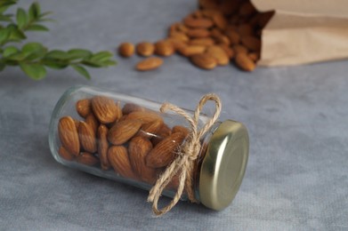Photo of Jar with delicious almonds on grey table