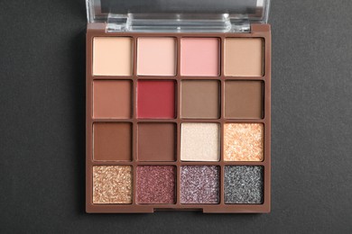 Photo of Colorful eyeshadow palette on dark background, top view