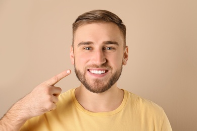 Young man with healthy teeth on color background