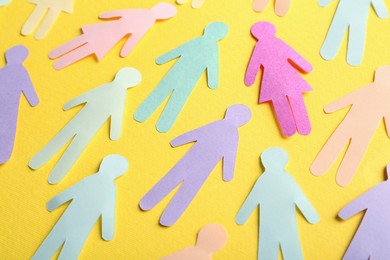 Many different paper human figures on yellow background. Diversity and inclusion concept