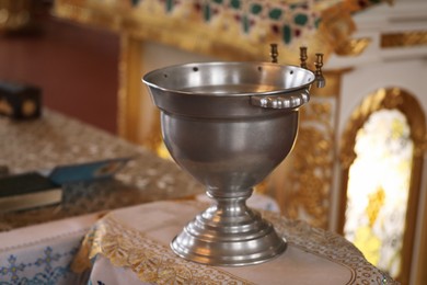 Silver vessel with holy water on stand in church. Baptism ceremony