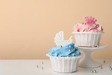 Photo of Delicious cupcakes with pink and light blue cream on white table, space for text. Baby shower party