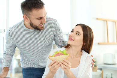 Photo of Happy couple with tasty sandwich at home