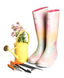 Watering can, flowers, rubber boots and gardening tools on white background