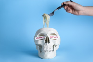Photo of Information warfare concept. Woman taking noodles from human skull, closeup. Media news influence