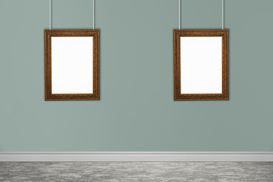 Frames with empty canvases on grey wall in modern art gallery. Space for design