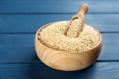 Bowl with sesame seeds and scoop on blue wooden table
