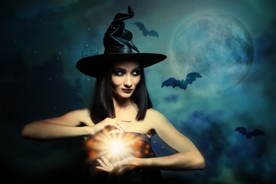 Image of Halloween fantasy. Scary witch conjuring on full moon night