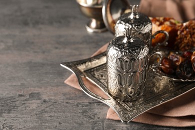 Photo of Tea, Turkish delight and date fruits served in vintage tea set on grey textured table, space for text