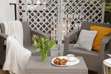 Photo of Different pillows, blanket, breakfast and beautiful tulips on rattan garden furniture outdoors