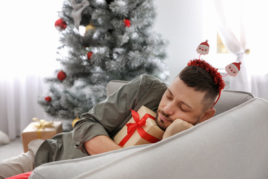 Man with gift box sleeping on sofa after New Year party