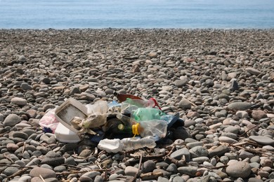 Pile of garbage on pebble beach near sea. Environmental Pollution concept