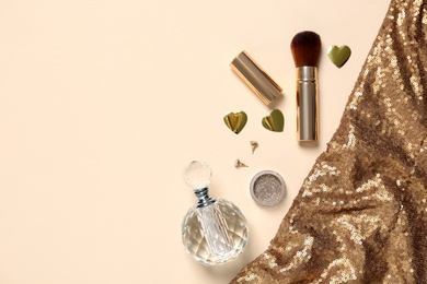 Photo of Flat lay composition with cosmetic products and shiny fabric, space for text