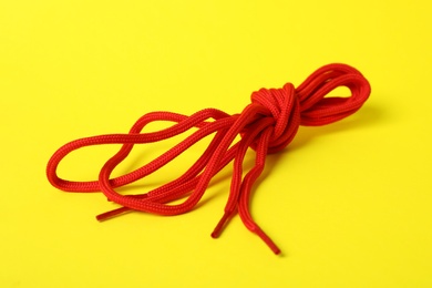 Red shoe laces tied in knot on yellow background