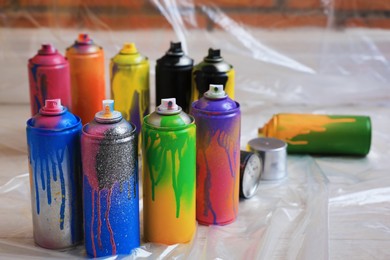 Used cans of spray paints on floor indoors. Graffiti supplies