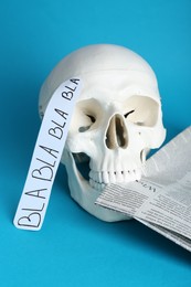 Photo of Information warfare concept. Useless nonsense in mind as result of media propaganda influence. Human skull with newspaper on light blue background
