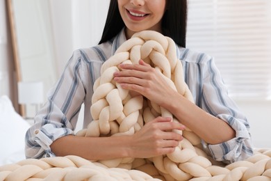 Woman with chunky knit blanket at home, closeup