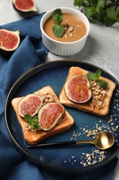 Photo of Tasty toasts served with fig, peanut butter and walnuts on light grey marble table, above view