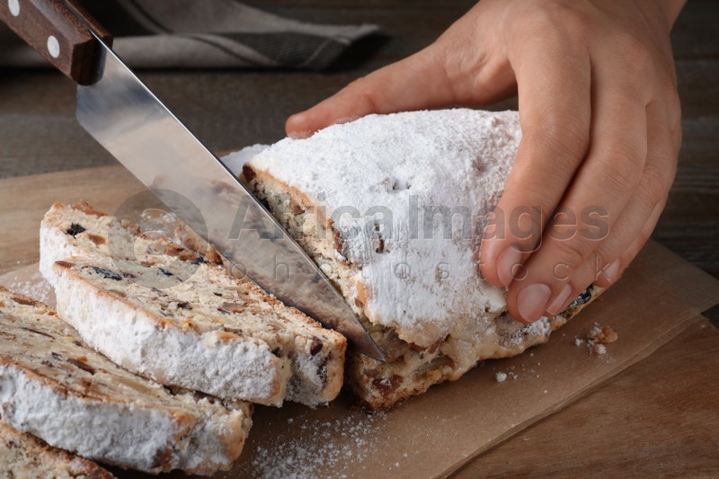 Woman cutting traditional Christmas Stollen at wooden board, closeup