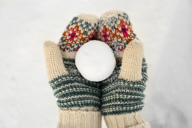 Woman in knitted mittens holding snowball outdoors, top view