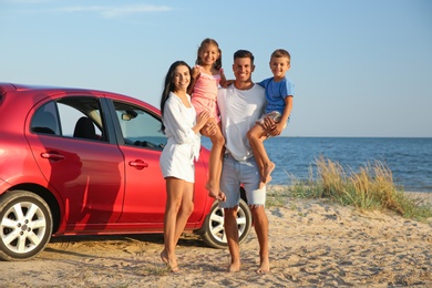 Happy family near car on sandy beach. Summer trip