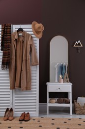Photo of Modern hallway interior with stylish white furniture and wooden hanger for keys on brown wall