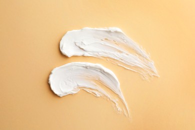 Sample facial cream on beige background, top view