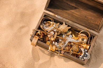Photo of Open wooden treasure chest on sand, above view. Space for text