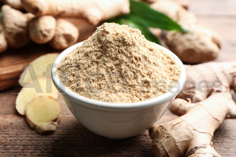 Dry ginger powder and fresh root on wooden table