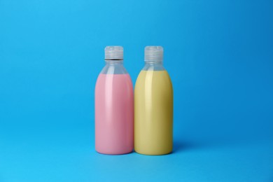 Photo of Bottles of detergents on light blue background. Cleaning supplies