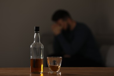 Addicted man at home, focus on table with alcoholic drink. Space for text