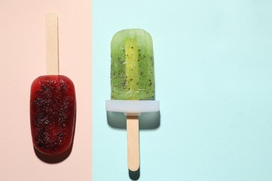 Photo of Tasty blackberry and kiwi ice pops on colorful background, flat lay with space for text. Fruit popsicle