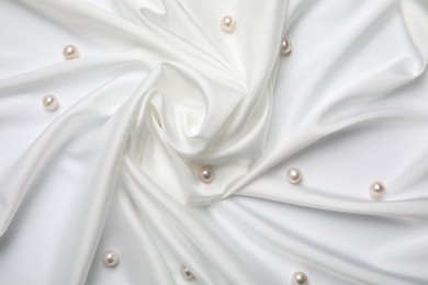 Beautiful pearls on white silk, flat lay