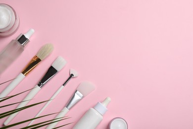 Different skin care products and brushes on pink background, flat lay. Space for text