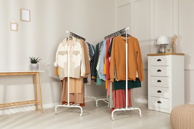 Racks with stylish clothes in cozy room interior. Fast fashion