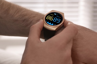 Image of Man measuring oxygen level with smartwatch indoors, closeup