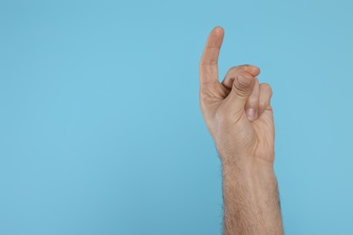 Man snapping fingers on light blue background, closeup of hand. Space for text