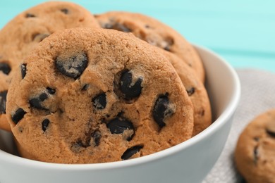 Bowl with many delicious chocolate chip cookies on table, closeup