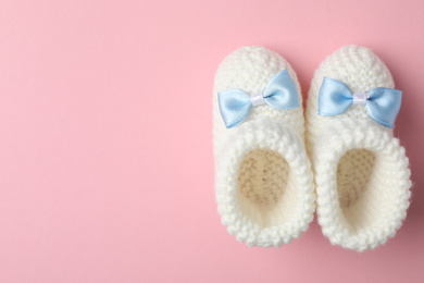 Photo of Handmade child's booties on pink background, flat lay with space for text