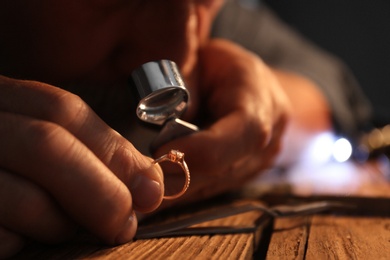 Male jeweler evaluating diamond ring in workshop, closeup view