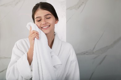 Photo of Beautiful teenage girl wiping face with towel at home, space for text