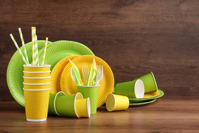 Set of bright disposable tableware on wooden table